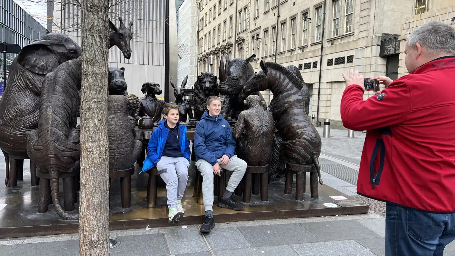 Father taking a photo of children on animal statues outside Paddington Station in London